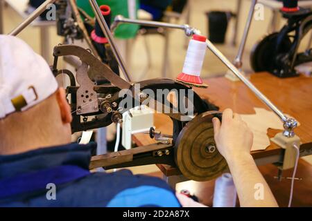 A man repairs shoes on a special retro sewing machine for leather Stock Photo