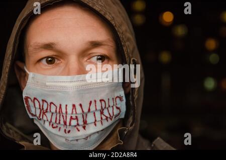 man in a hood with a medical mask on his face with the inscription Coronavirus in the dark. Concept of health care, medicine Stock Photo