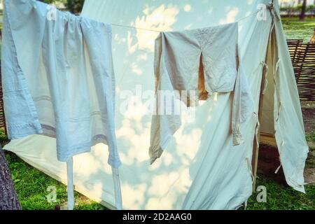 Clothesline on which to dry retro shirts and pants. White clothes drying in the open air. Stock Photo