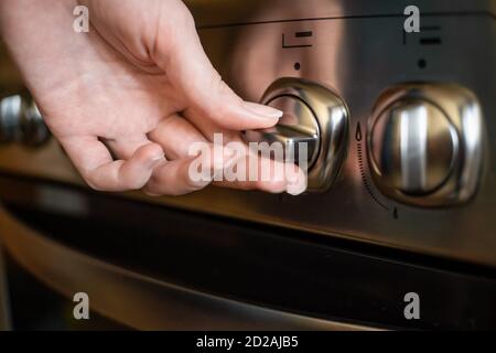 woman's hand turns on a switch on a stainless steel gas stove close up Stock Photo
