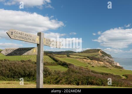 Close up of a sign post pointing toward Golden Cap mountain with Golden Cap mountain in the background Stock Photo