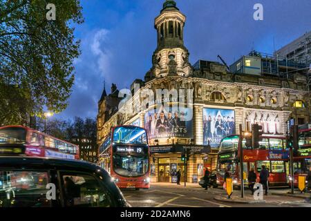 Red buses and black taxis passing the Shaftesbury Theatre at night in the West End of London. Stock Photo