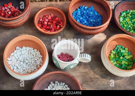 Retro mosaic cubes in clay pots. Creating patterns from processed stones. The material for decorating the walls of houses and dishes in ancient times, Stock Photo