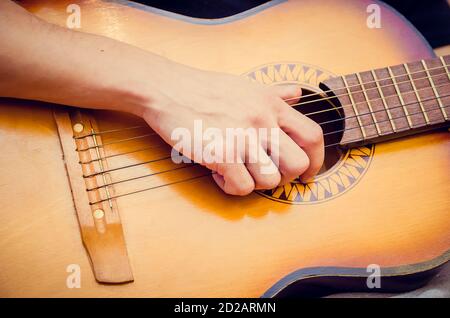 man plays a brown guitar in close-up Stock Photo