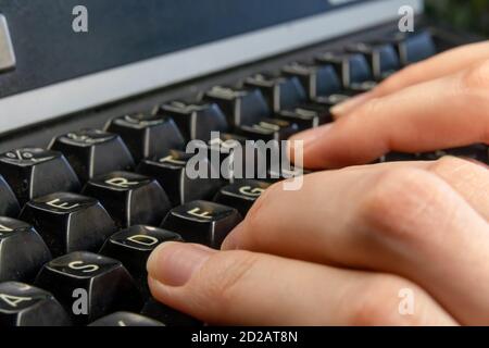 Women's hands are typing on an old dirty black typewriter close up Stock Photo