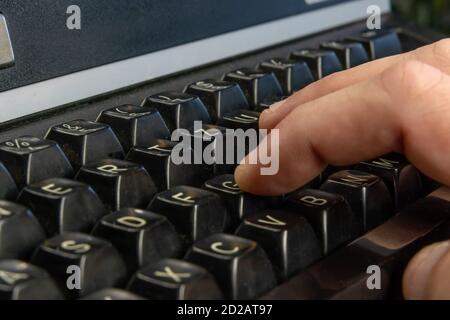 Men's hands are typing on an old dirty black typewriter close up Stock Photo