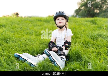 Little pretty girl on roller skates at a park. Young happy skater Stock Photo