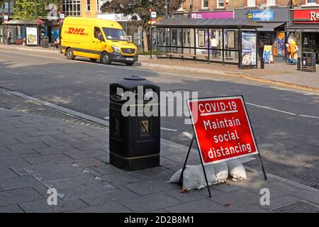 Covid 19 maintain social distancing sign coronavirus lockdown quiet Brentwood Essex shopping high street 9.28am weekday DHL parcel delivery van in  UK Stock Photo