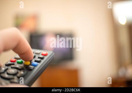 man's hand with the remote is pointed at the TV. Focus on the hand with the remote Stock Photo