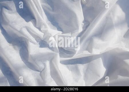 white rippled textured fabric background illuminated by the rays of the sun. Luxurious background design  Stock Photo