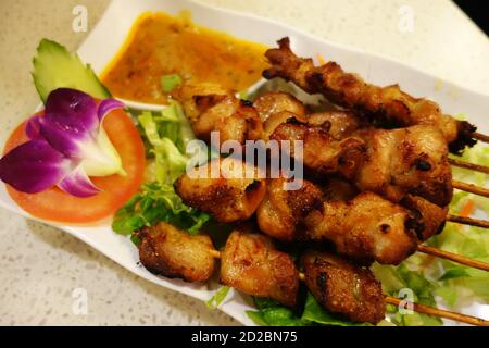 Delicious chunks of chicken presented with satay sauce and flower salad, Hong Kong Stock Photo