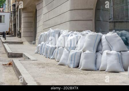 Lots of bags of cement or sand near the wall for building or laying tiles close up Stock Photo