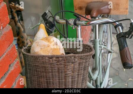 Bread in a wicker basket on a bicycle near a brick wall close-up Stock Photo