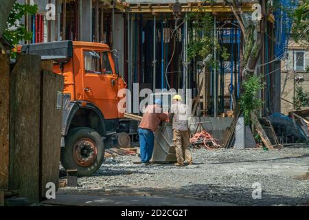 Builders in helmets stand back and talk around the truck Stock Photo