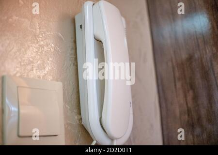 Entrance tube of the intercom on a background of a light wall and a switch close-up Stock Photo