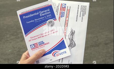 Close up of a woman's hand holding mail ballot and voter booklet. Illustrative editorial taken in Vista, CA / USA on October 6, 2020.