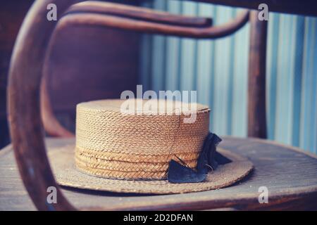 Old straw hat on vintage shabby chair, close-up Stock Photo