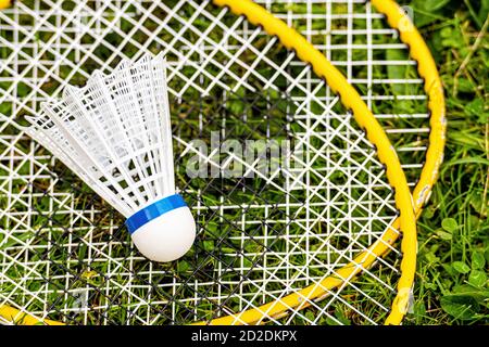 white shuttlecock close-up on yellow badminton rackets in the green grass, top down view Stock Photo