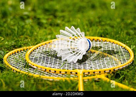 white shuttlecock on yellow badminton rackets in the green meadow Stock Photo