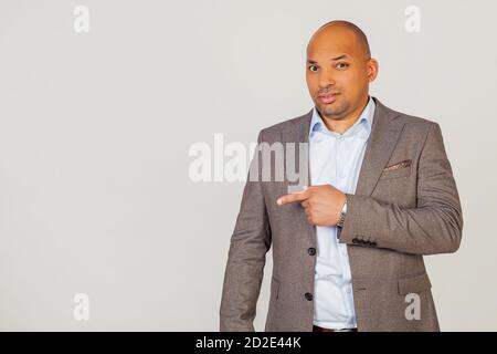 Male African American businessman in a jacket pointing with hand and finger with an expression of disgust. Copy space. on a gray background Stock Photo