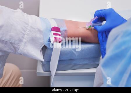 Taking blood for analysis for coronavirus with a syringe from a vein. Doctor injects a woman hand with a syringe for a vaccine, lifestyle Stock Photo