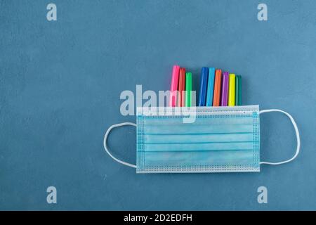 Medical mask and multi-colored markers on a blue background Stock Photo