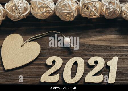 New Year 2021. Gold numbers, decorations and a glowing garland on a dark wooden table. Merry Christmas and Happy New Year. Top view. Close up. Stock Photo
