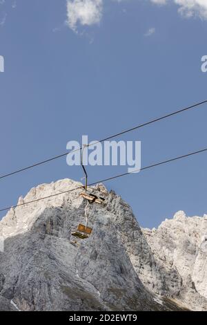 Abandoned chairlifts against a rocky mountain in Agordo, on the Italian Dolomites, in the summer. Stock Photo