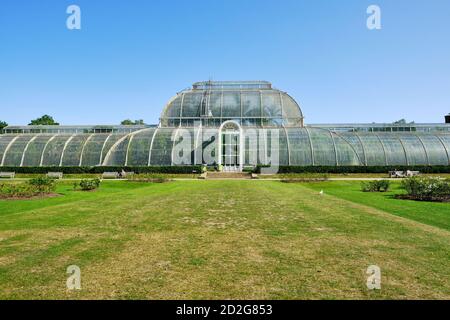 The Palm House in the Royal Botanic Gardens, Kew in Richmond upon Thames, against clear blue sky. Seen from the Rose Garden. Stock Photo