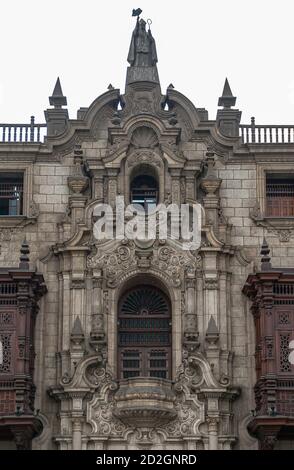 Lima, Peru - December 4, 2008: Palace of the Archbishop. Closeup of top of main entrance with sculpted facade featuring balcony and statue of Saint Tu Stock Photo