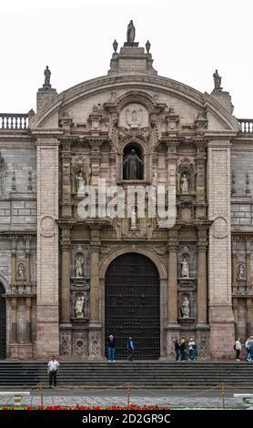 Lima, Peru - December 4, 2008: Basilica Cathedral of St. John the Apostle is gray stone building. Closeup of main entrance with statues of Sacred hear Stock Photo