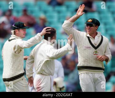 Matthew Hayden of Australia (R) is joined by team mate Michael Clarke (L) as they congratulate Stuart MacGill (C) who had World XI's Andrew Flintoff caught for 15 runs on day four of the cricket Super Test in Sydney October 17, 2005. The World XI were struggling to avoid a massive defeat in the super test against Australia after losing three quick wickets on the fourth day on Monday.REUTERS/Will Burgess