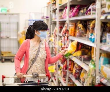young woman wearing protective mask and buying food in supermarket Stock Photo
