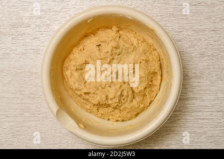 Mixed mixture of yeast dough ingredients, ready for lifting. The process of cooking in a light round large plastic bowl. Stock Photo