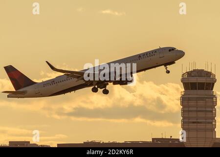 Washington DC, USA 10/03/2020: Sunset view of an Airbus A321 model airplane operated by Delta Airlines is passing in front of  Airport Control Tower a Stock Photo