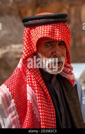 Petra, Jordan 04/02/2010: Portrait of an elderly Arabic man wearing traditional clothes including a red keffiyeh, agal, and jubba thobe. He has gray b Stock Photo