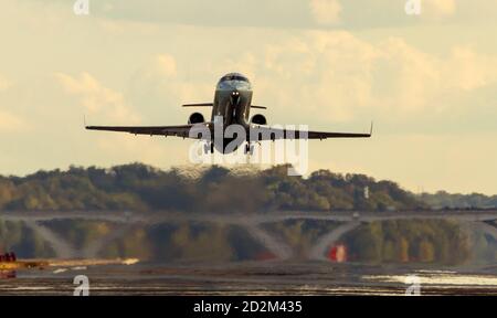 A passenger Airplane is taking off from the runway of an airport at sunset. The exhaust and evaporation of jet fuel creates massive blurring and air p Stock Photo