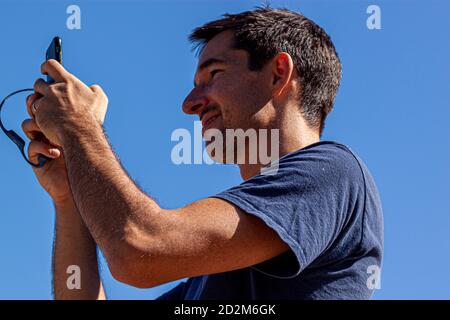 Great Falls, VA, USA 10/03/2020: A caucasian man with short hair and short beard is holding a smartphone in his hands. Image shows his chest and above Stock Photo