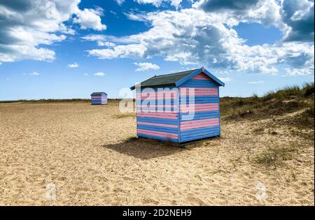 Great Yarmouth beach cabins in a summer day, traditional UK cabin on an English East Coast, blue and pink horizontal stripes, sky with clouds Stock Photo
