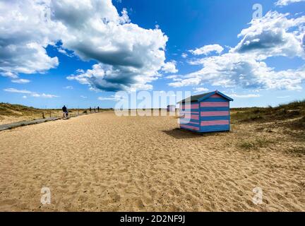Great Yarmouth beach cabins in a summer day, traditional UK cabin on an English East Coast, blue and pink horizontal stripes, sky with clouds no peopl