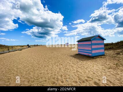 Great Yarmouth beach cabins in a summer day, traditional UK cabin on an English East Coast, blue and pink horizontal stripes, sky with clouds Stock Photo