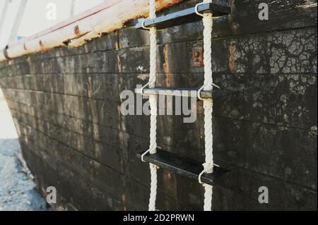 rope sea ladder on Board an old wooden black ship Stock Photo