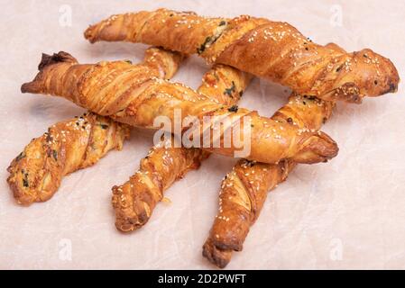 Twisted puff pastry sticks on white paper parchment, wood table Stock Photo