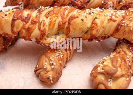Twisted puff pastry sticks on white paper parchment, wood table Stock Photo