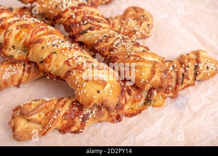 Twisted puff pastry sticks on white paper parchment, wood table Stock Photo