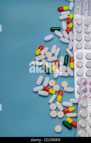 Tablets in blisters and scattered capsules of various medicines on blue background. Antibiotics and aspirin for health. Medicine and pharmacy concept. Stock Photo