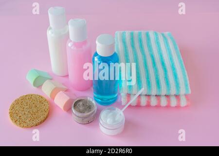 Cosmetics for cleansing the skin of the face. Lotion, scrub, cream, wash gel, sponge and towels on pink wooden background. Concept of daily skin care Stock Photo