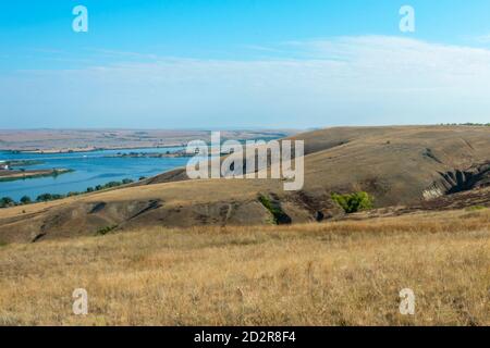 Beautiful landscape of nature. The river is meandering between the hills in the Volga steppe. Ravines and blue sky on a summer day. Soft focus. Stock Photo