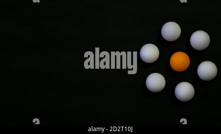 Leadership concept photo. An orange ball circled by white ball with black background Stock Photo
