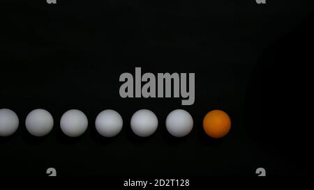 Leadership concept photo. A line up of an orange follow by white ball with black background Stock Photo